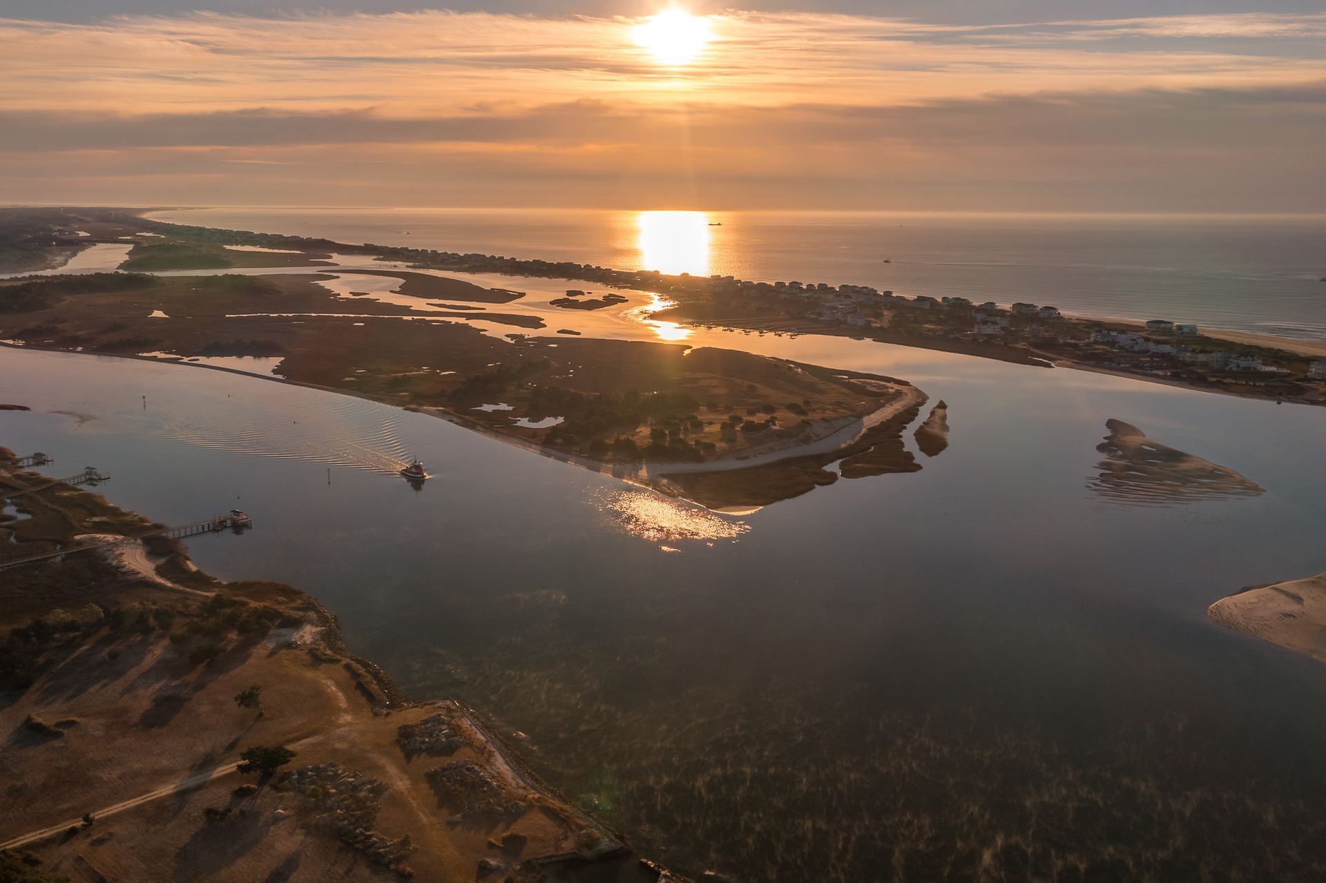 Sunset over a calm coastal inlet with islands and glowing reflections on the water