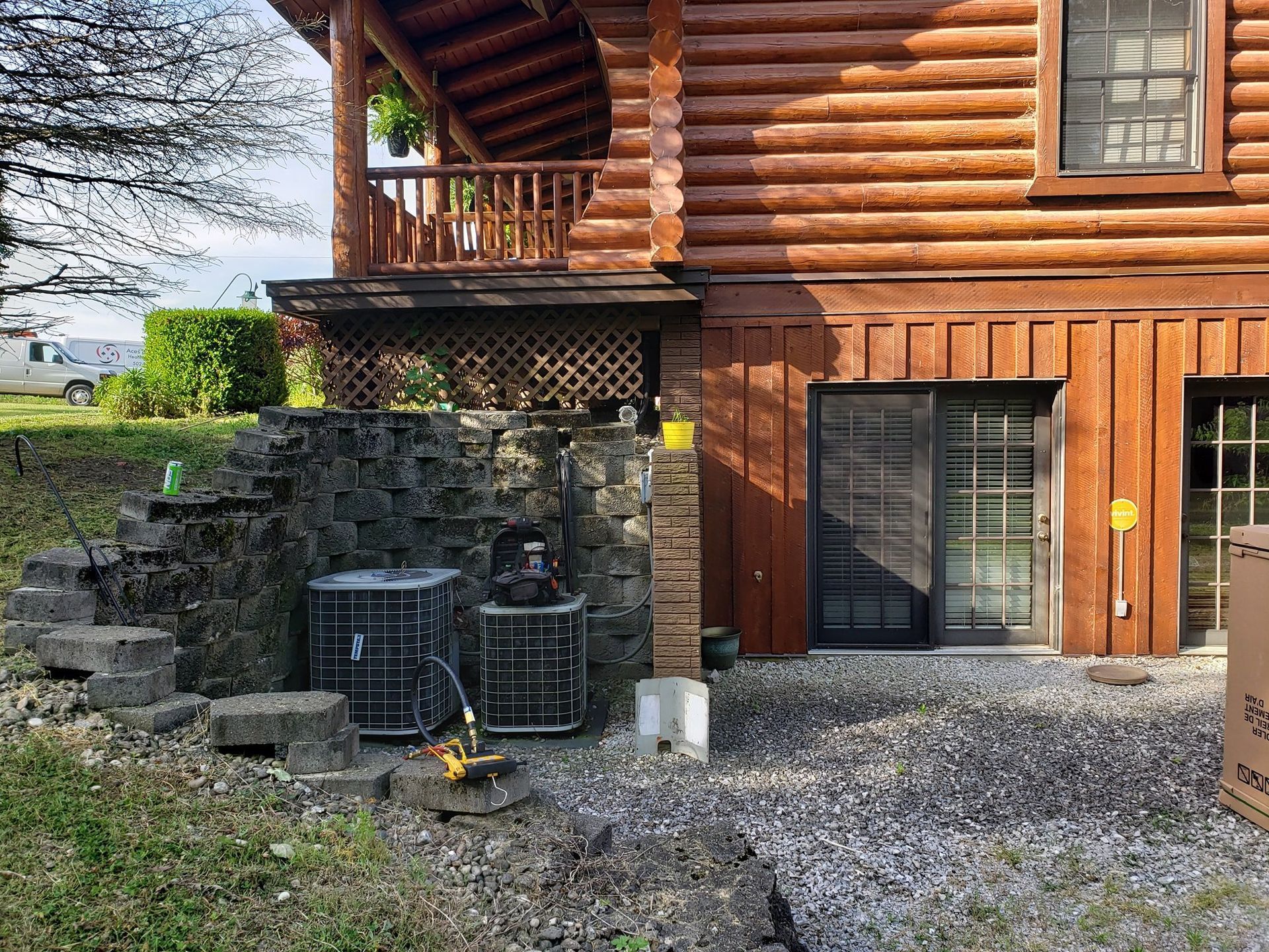 A log cabin with two air conditioners on the side of it.
