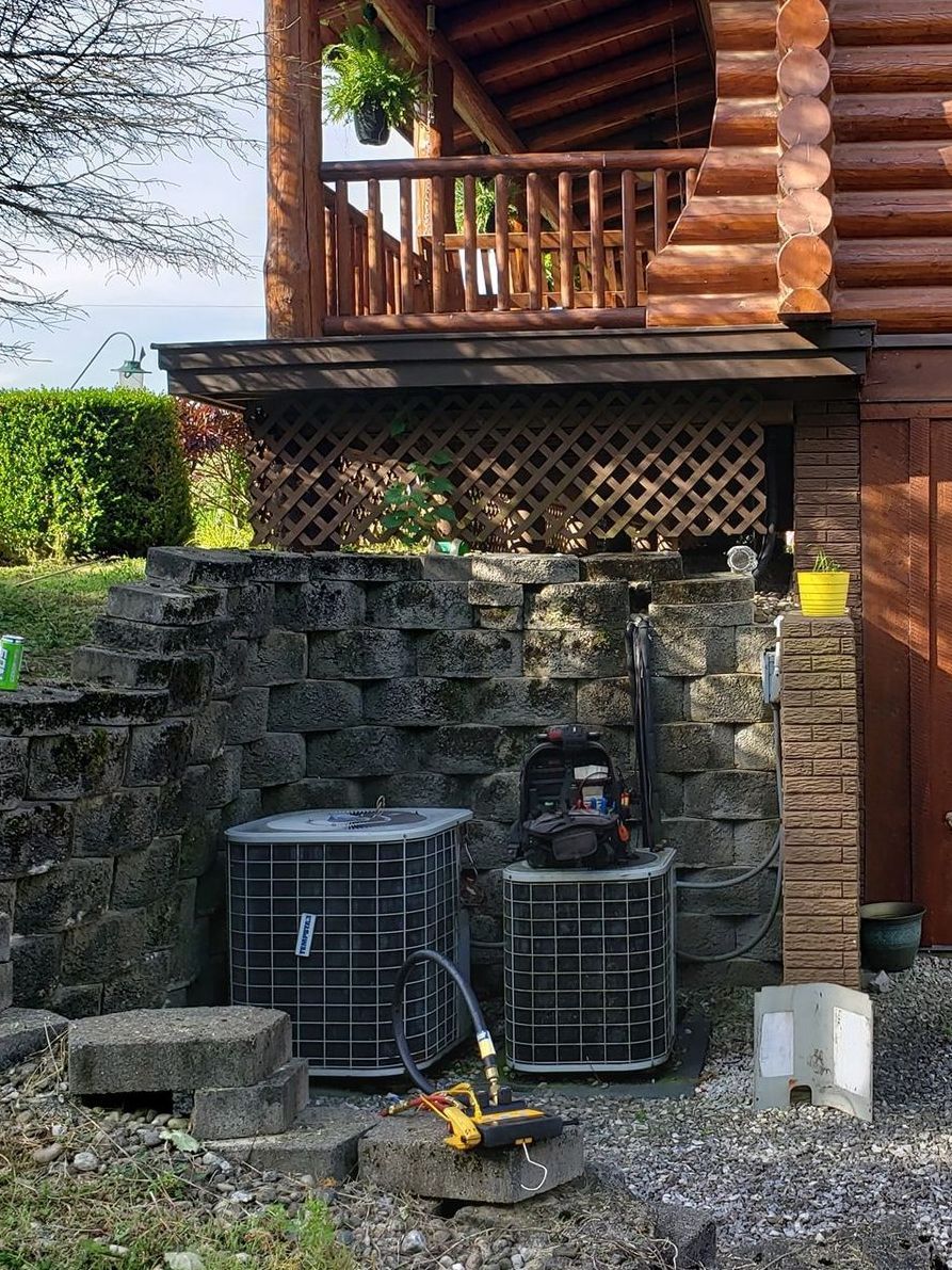 A log cabin with two air conditioners on the side of it.