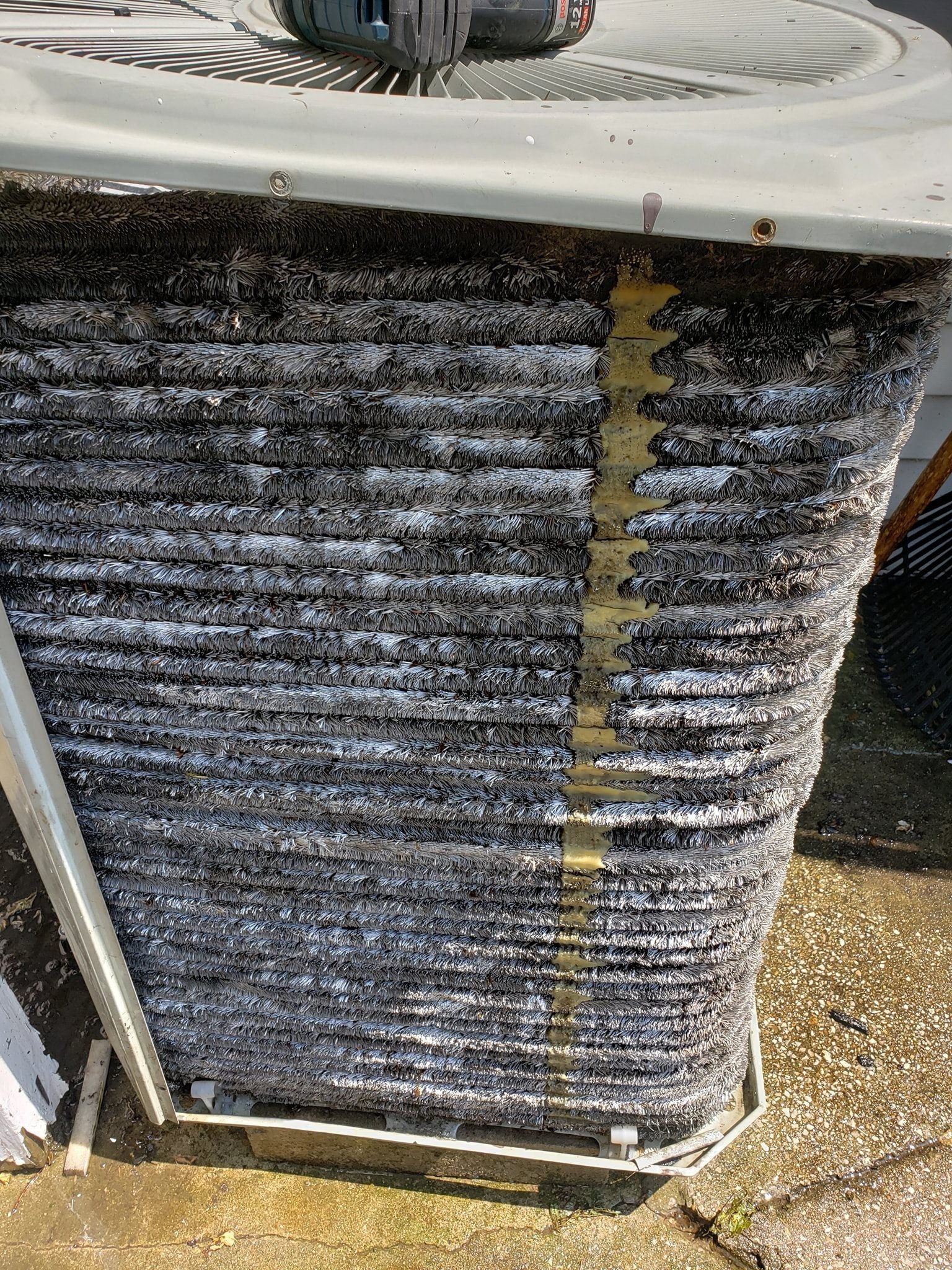A close up of a dirty air conditioner on the ground.