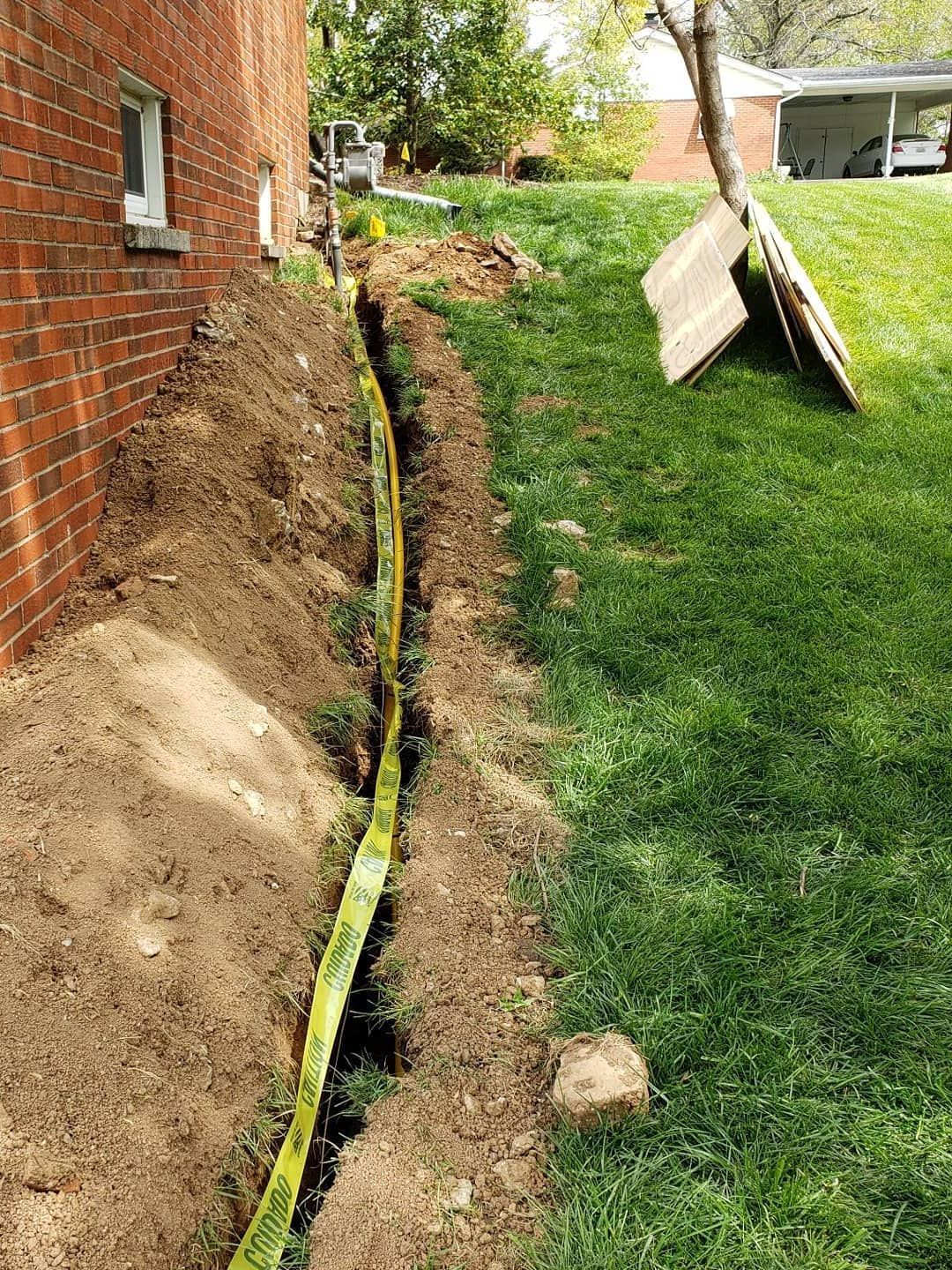 A drain pipe is being installed on the side of a brick building.