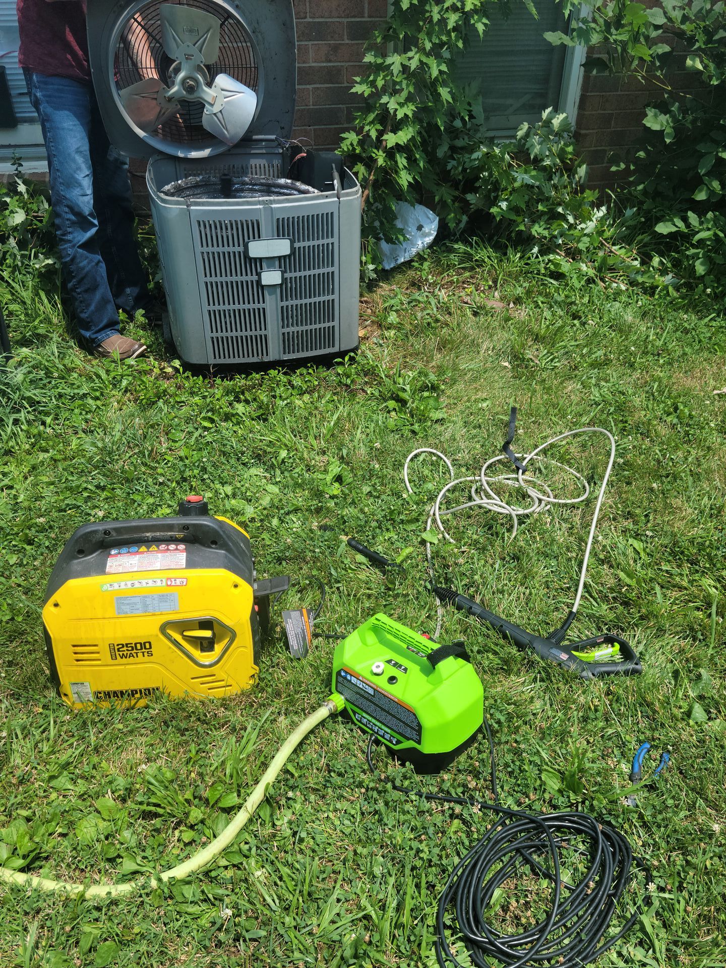 A man is working on an air conditioner in a backyard.