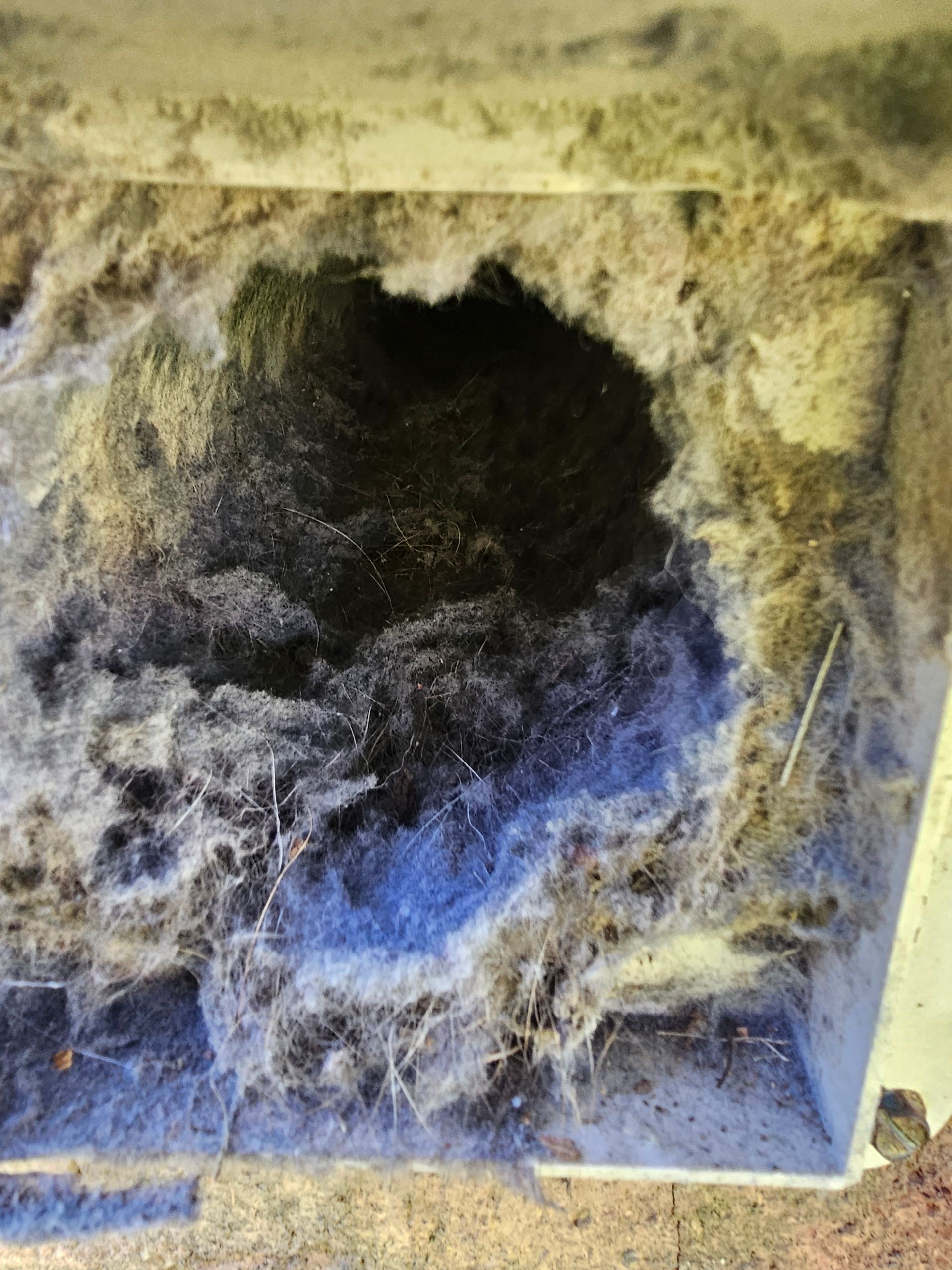 There is a hole in the wall that is covered in dust.