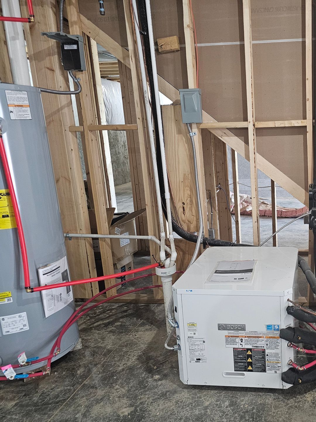 A water heater is sitting in a room next to a wooden wall.
