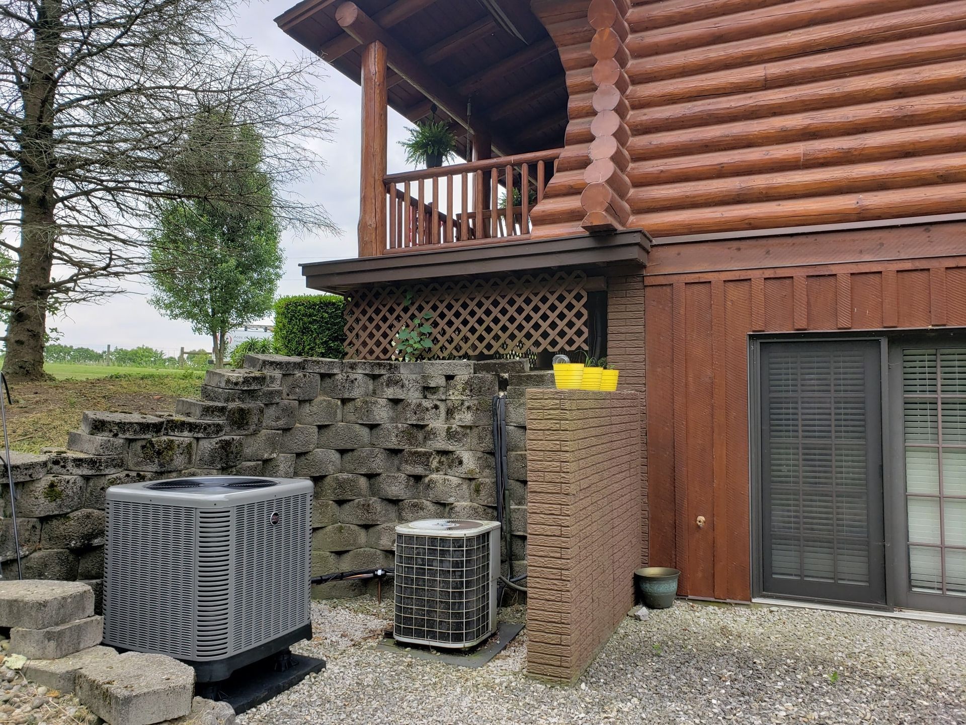 A log cabin with two air conditioners on the side of it.