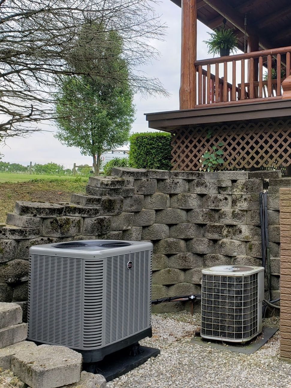 A couple of air conditioners are sitting outside of a house.
