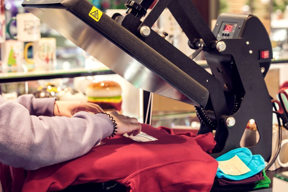 A Person Is Using a Heat Press Machine to Print a Shirt — Imsprint in Maitland, NSW
