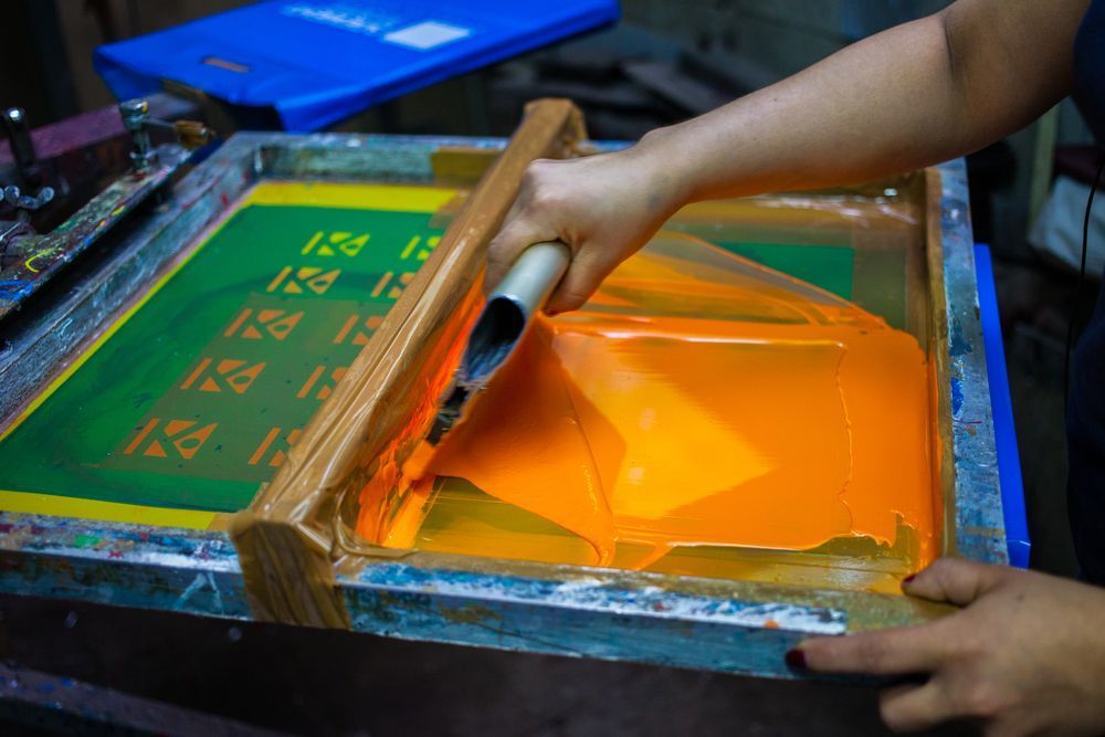 A Person Is Using a Screen Printing Machine to Print on A Piece of Paper — Imsprint in East Maitland, NSW
