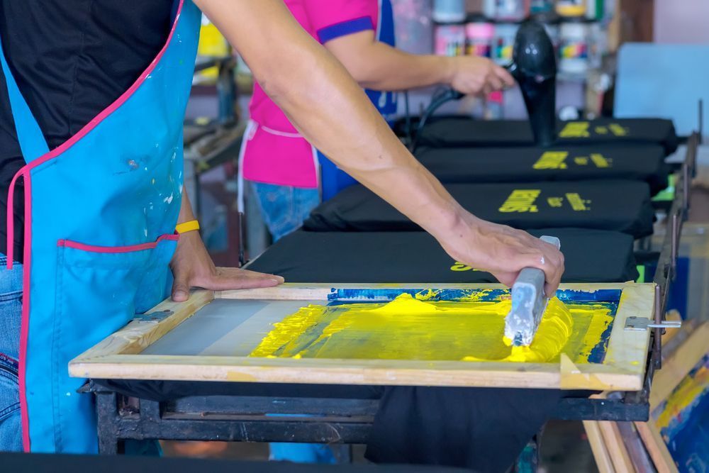 A Person Is Using a Screen Printing Machine to Print a T-Shirt — Imsprint in Maitland, NSW