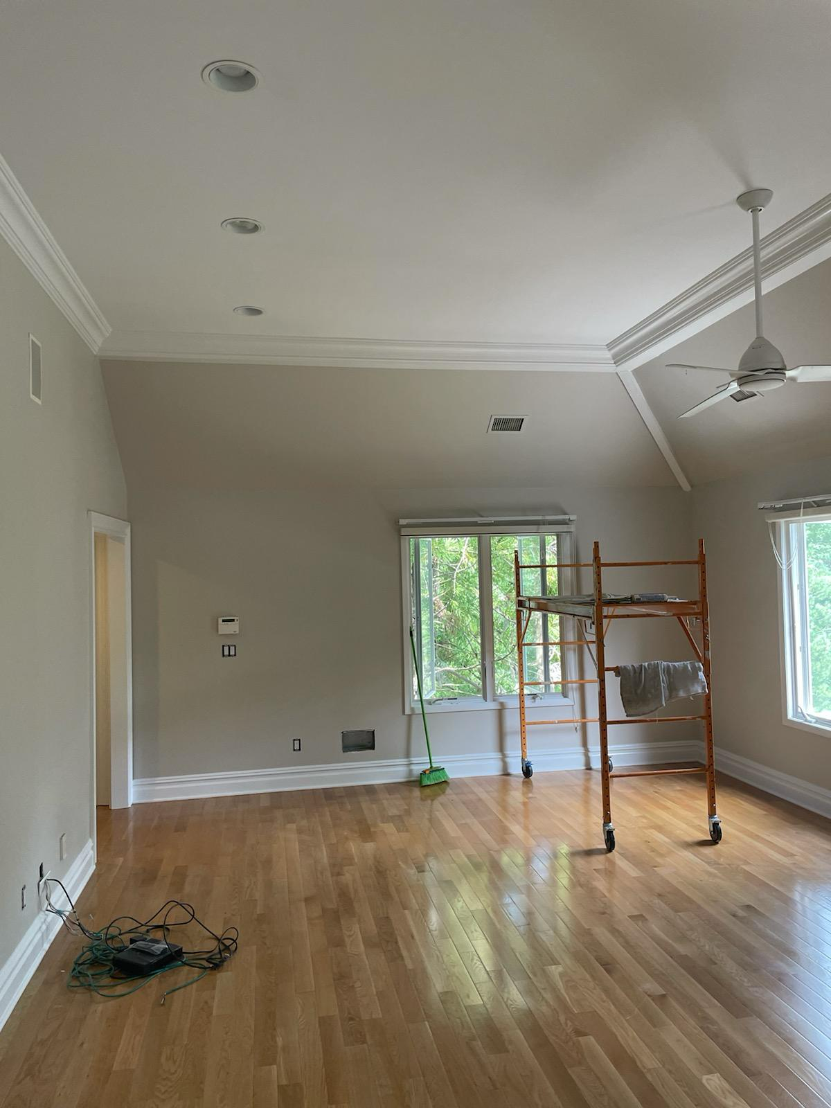 An empty living room with hardwood floors and a ceiling fan.