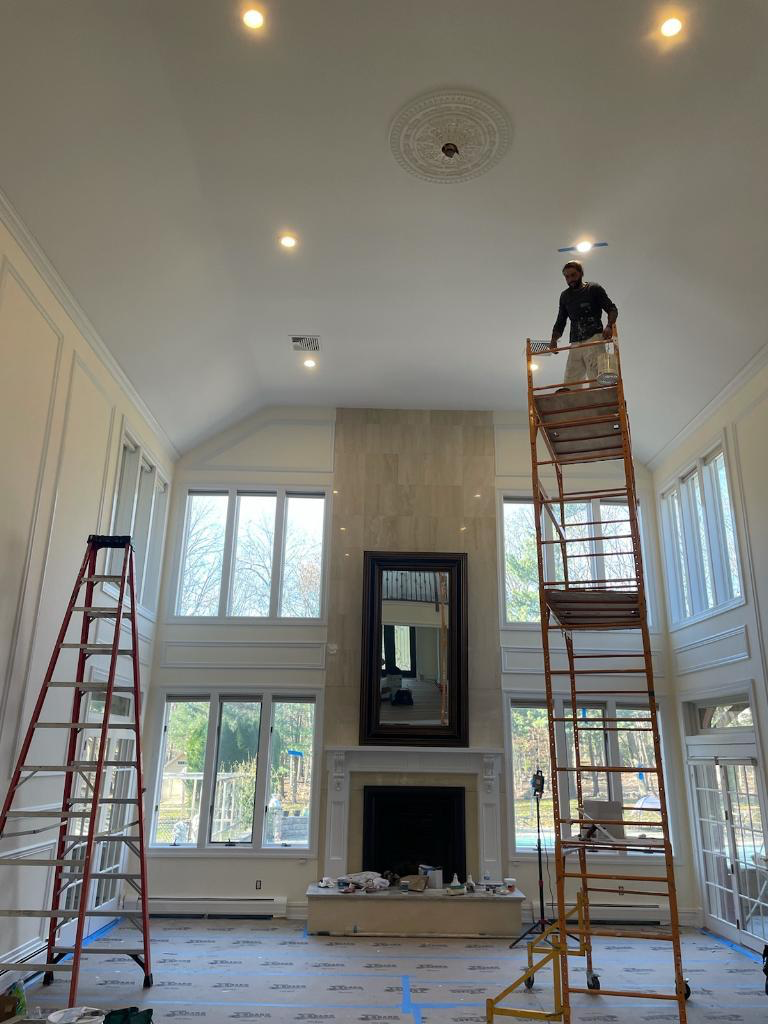 A man is standing on a ladder in a living room.