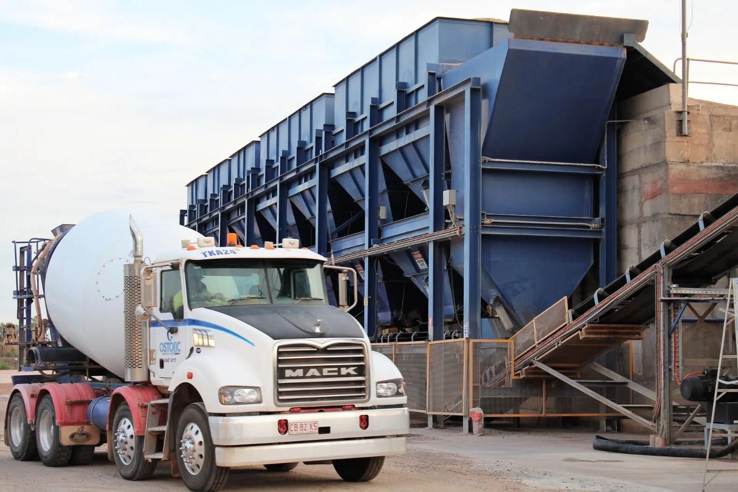A Concrete Mixer Truck Parked Next to a Blue Concrete Batch Plant