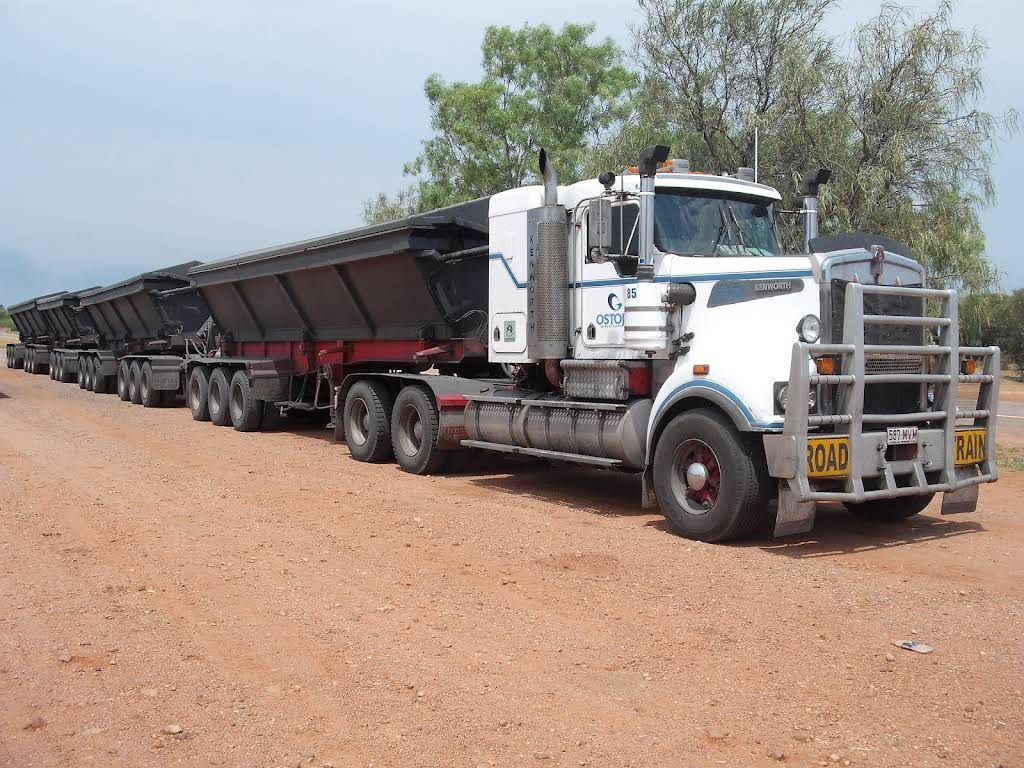 A Row of Semi Trucks Are Parked on a Dirt Road — Ostojic Group in Berrimah, NT