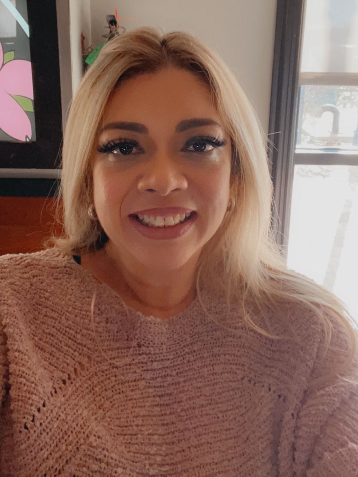 A woman in a pink sweater is smiling for the camera.
