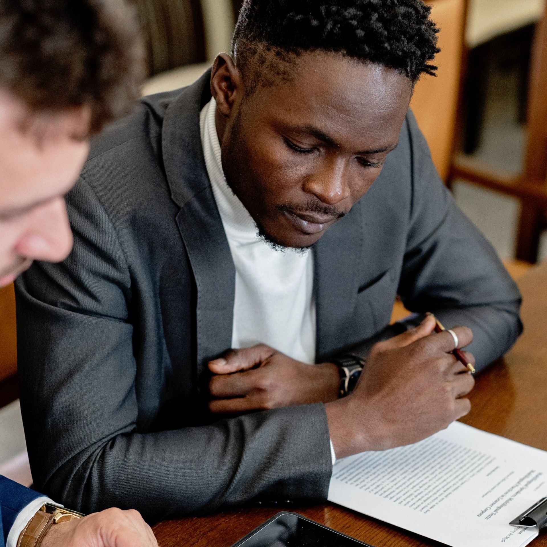 Two men are sitting at a table looking at a piece of paper.