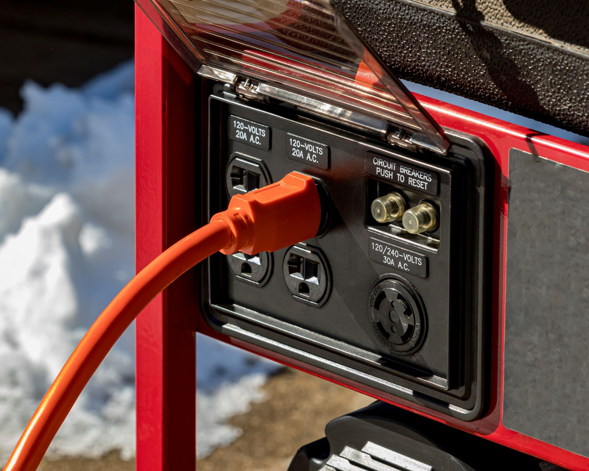 Red generator panel with an orange power cord plugged in. 
