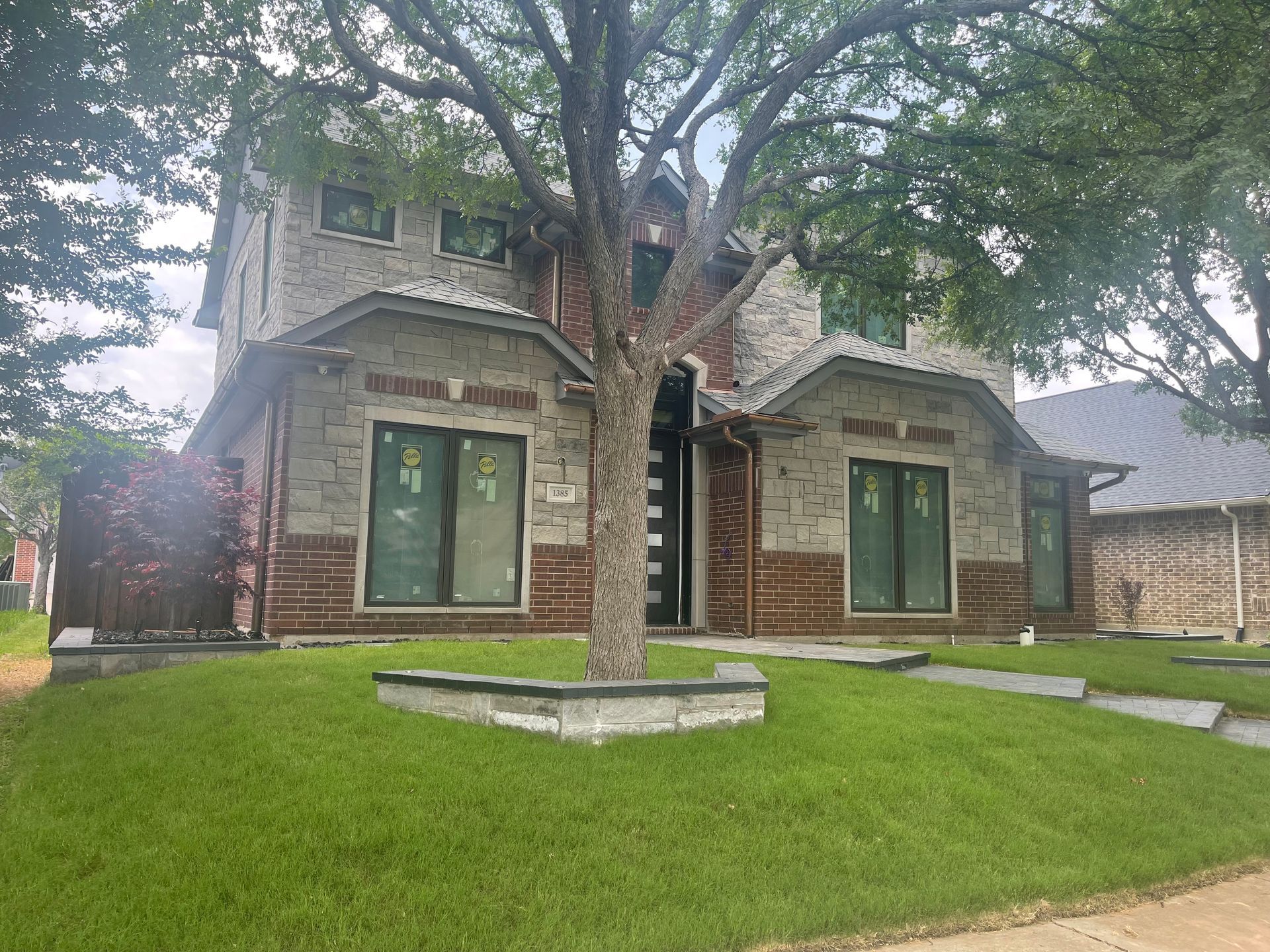 A brick house with a tree in front of it.