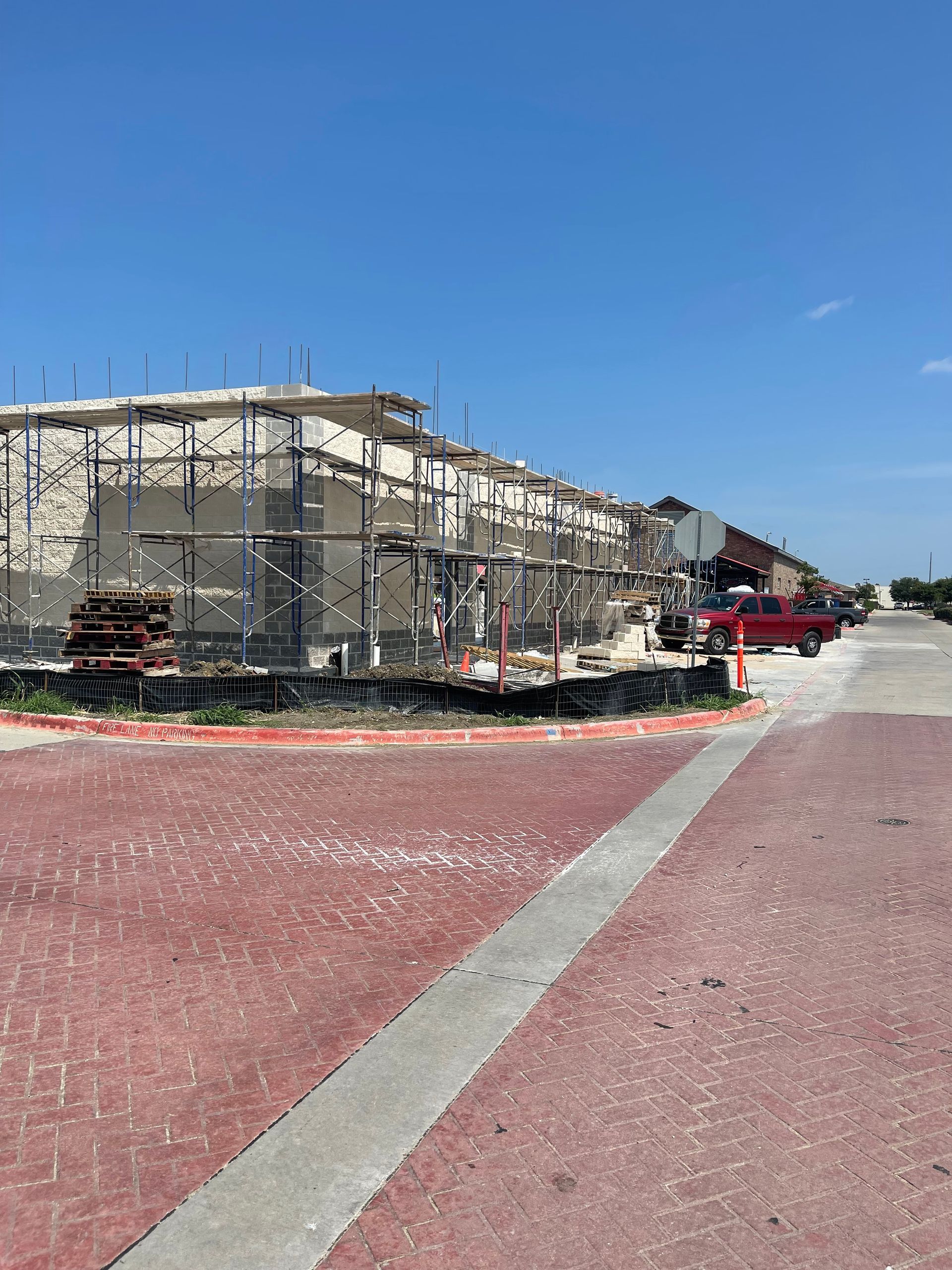 A red truck is parked in front of a building under construction.