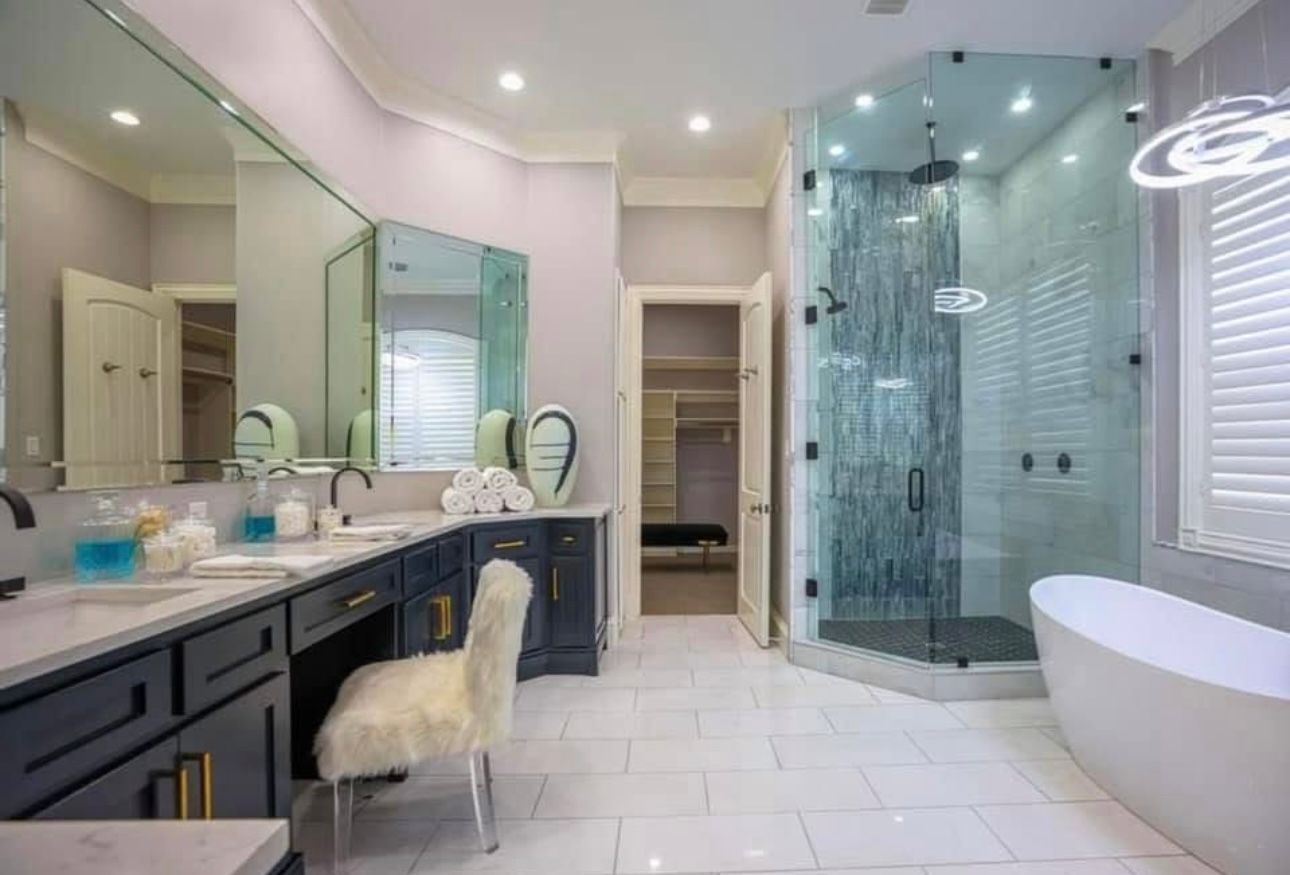 A bathroom with a tub , sink , shower and mirrors.