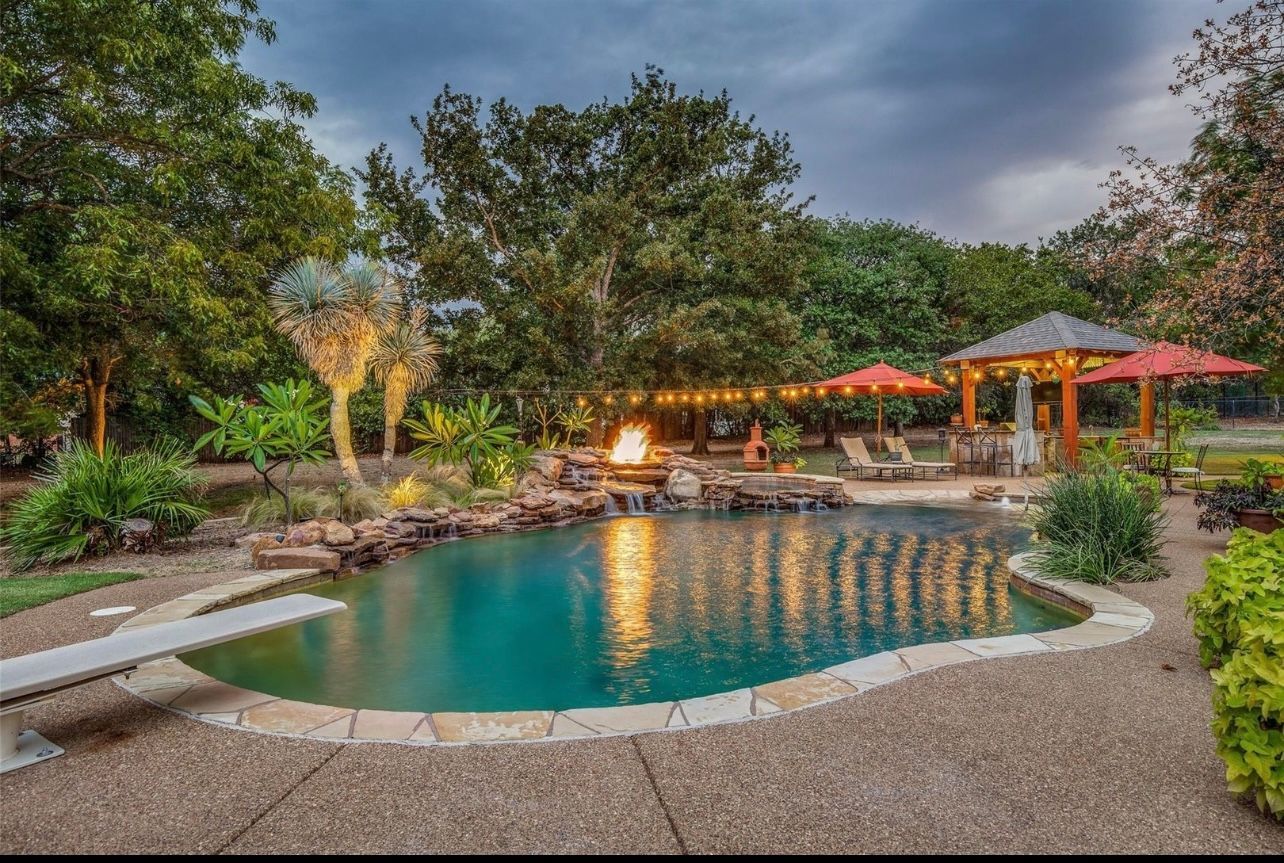 A large swimming pool with a fire pit in the middle of it