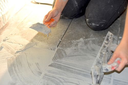 A worker performing grout repair services. A worker performing grout repair services.