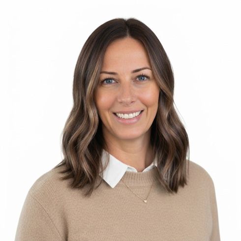 Woman with gray hair smiles, wearing a black top, against a light gray background.