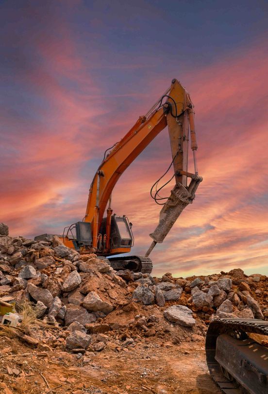 A bulldozer with torn up ground around it and pretty sunset in the sky behind it