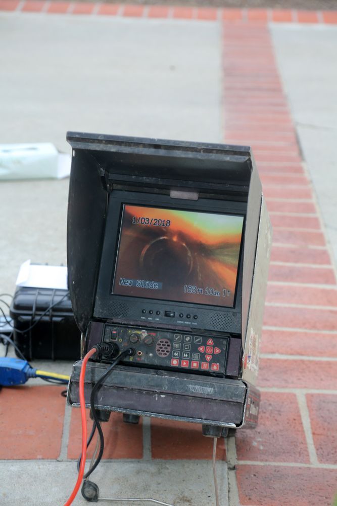 A small black portable monitor setup on a tiled floor, showing a sunset scene with cables attached.