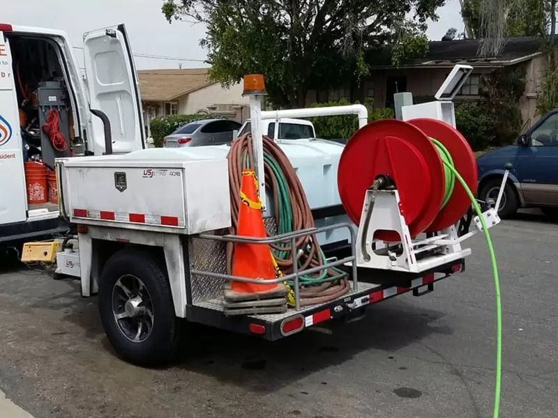 Utility truck with hose reels and equipment parked on a street, rear side view