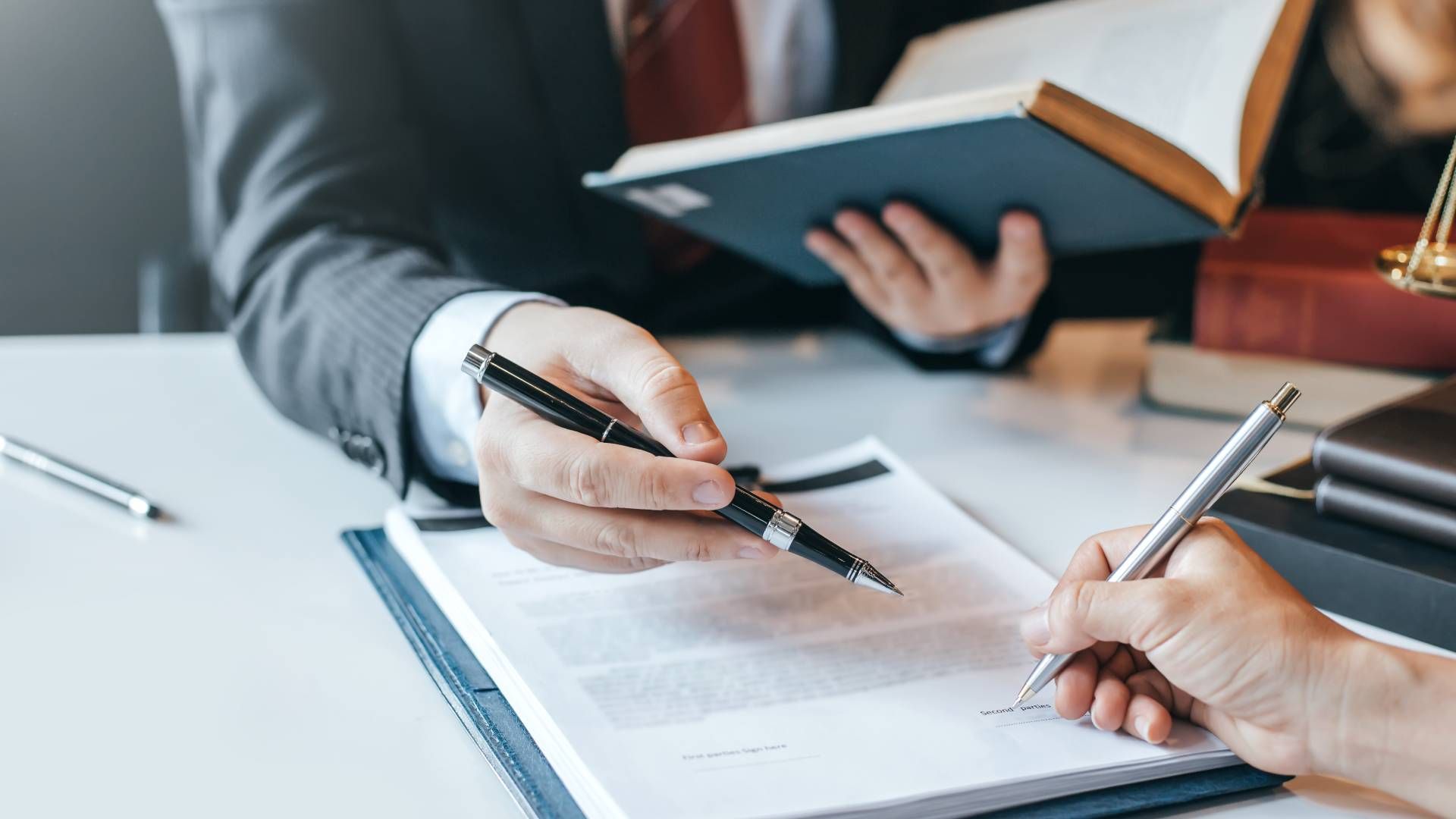 A man and a woman are sitting at a table signing a document.
