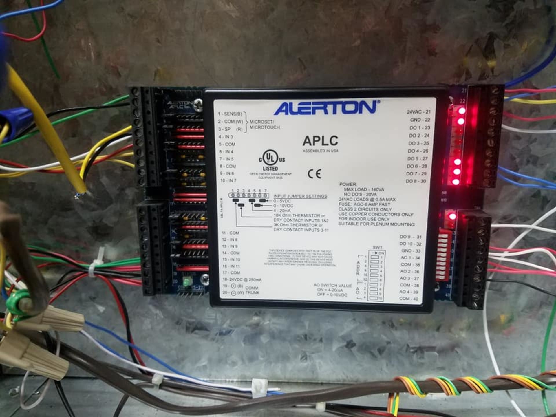 A device that says alerton aplc is surrounded by wires