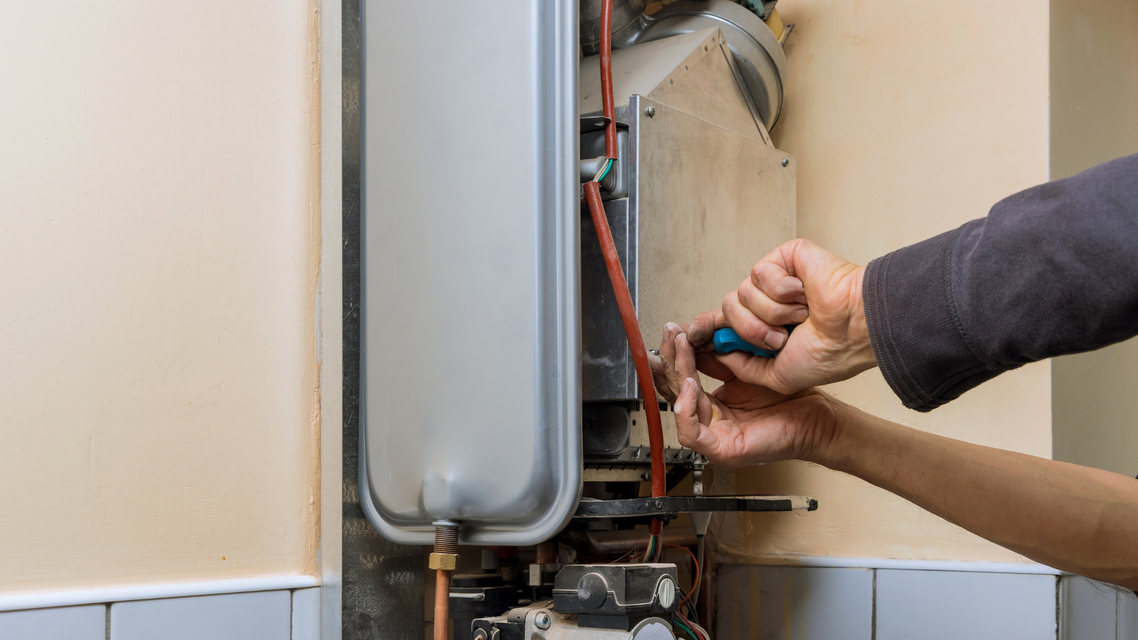 Technician performing heating repair on home water heating system—part of emergency heating service near you