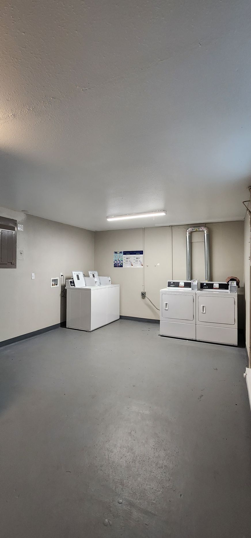 Laundry room with white washers and dryers along the walls on a gray floor.