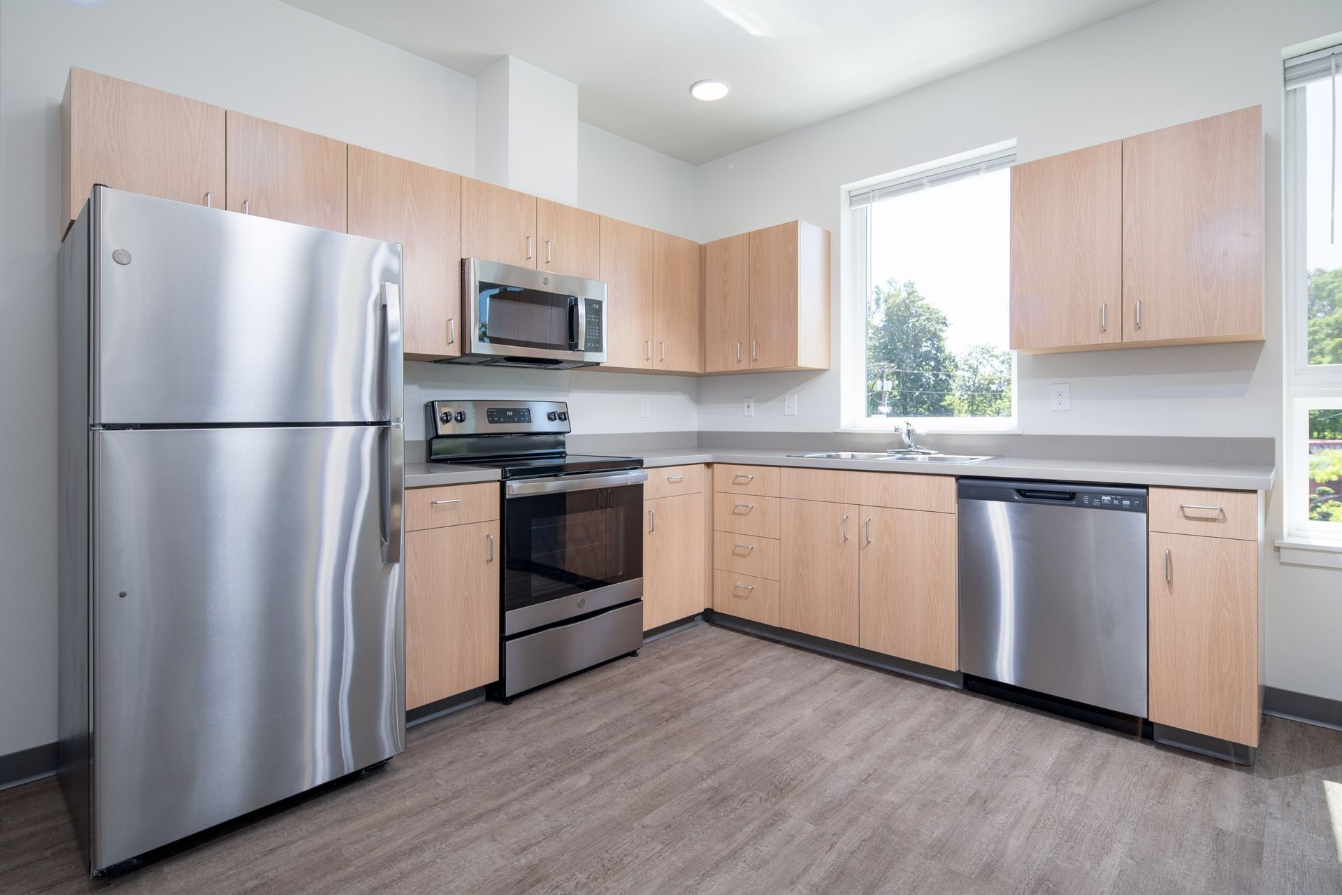 Modern kitchen with stainless steel appliances, light wood cabinets, and a large window