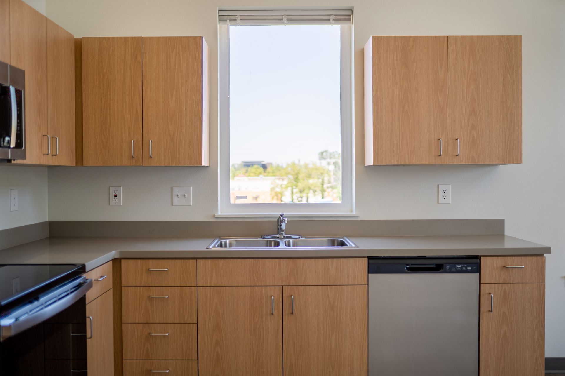 Modern kitchen with wood cabinets, gray countertops, and a window above the sink