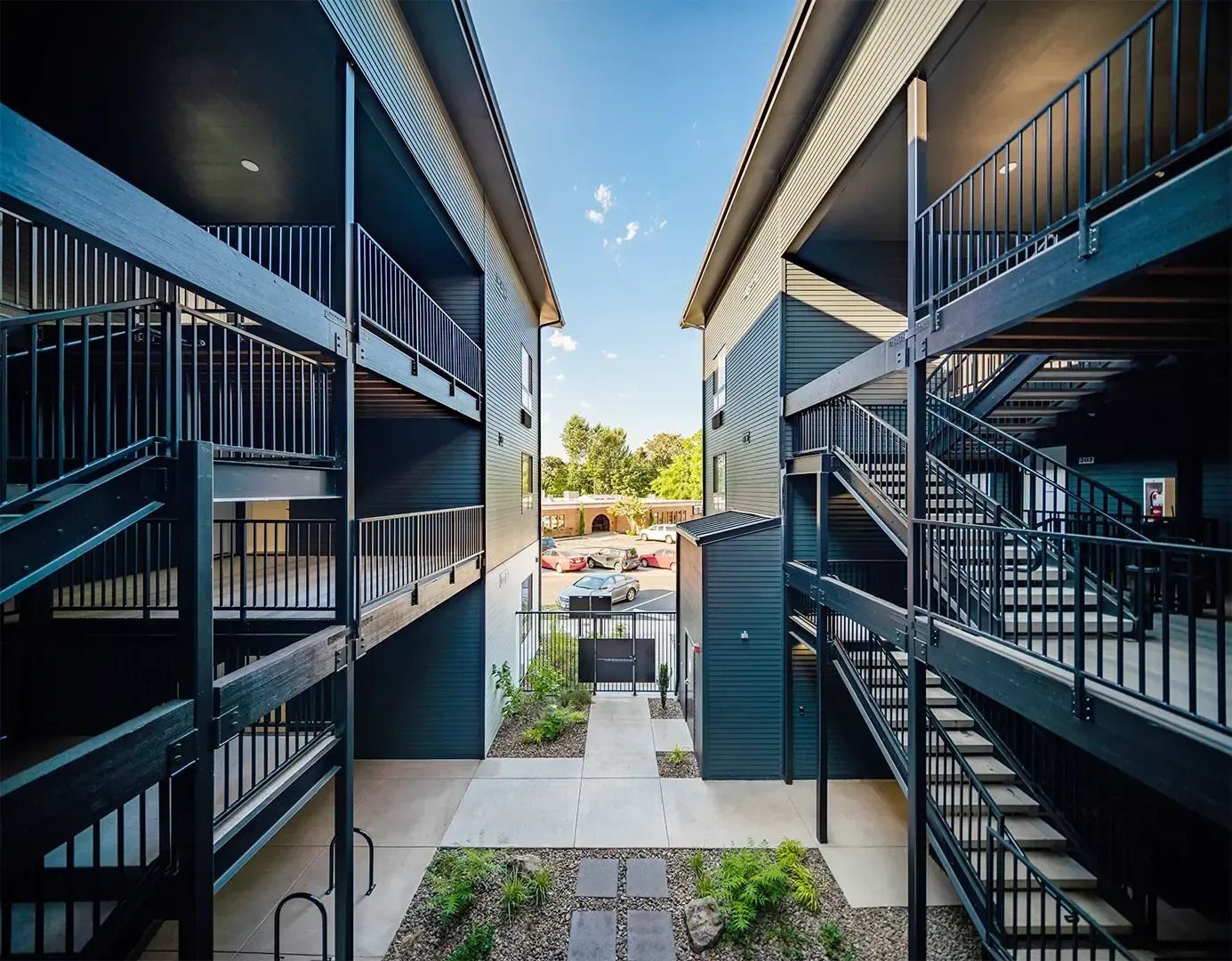 Modern apartment courtyard between dark staircases, leading to a bright outdoor pool area