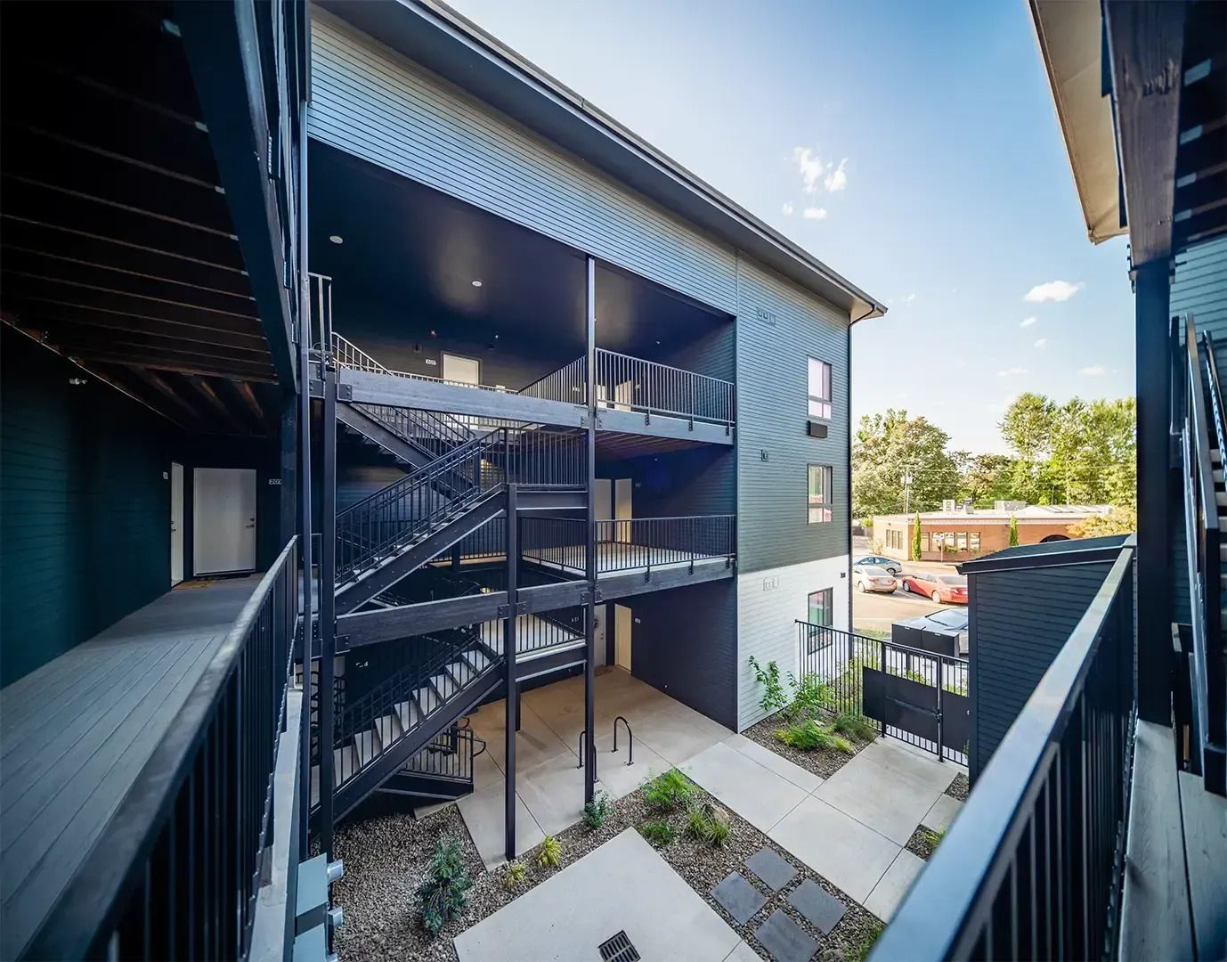 Apartment courtyard with black metal staircases, balconies, and a bright blue sky