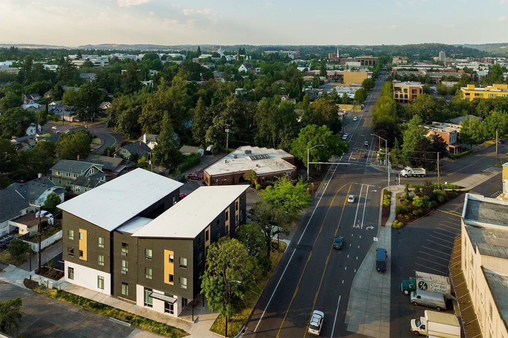 Aerial view of a suburban street with buildings, trees, and cars at an intersection