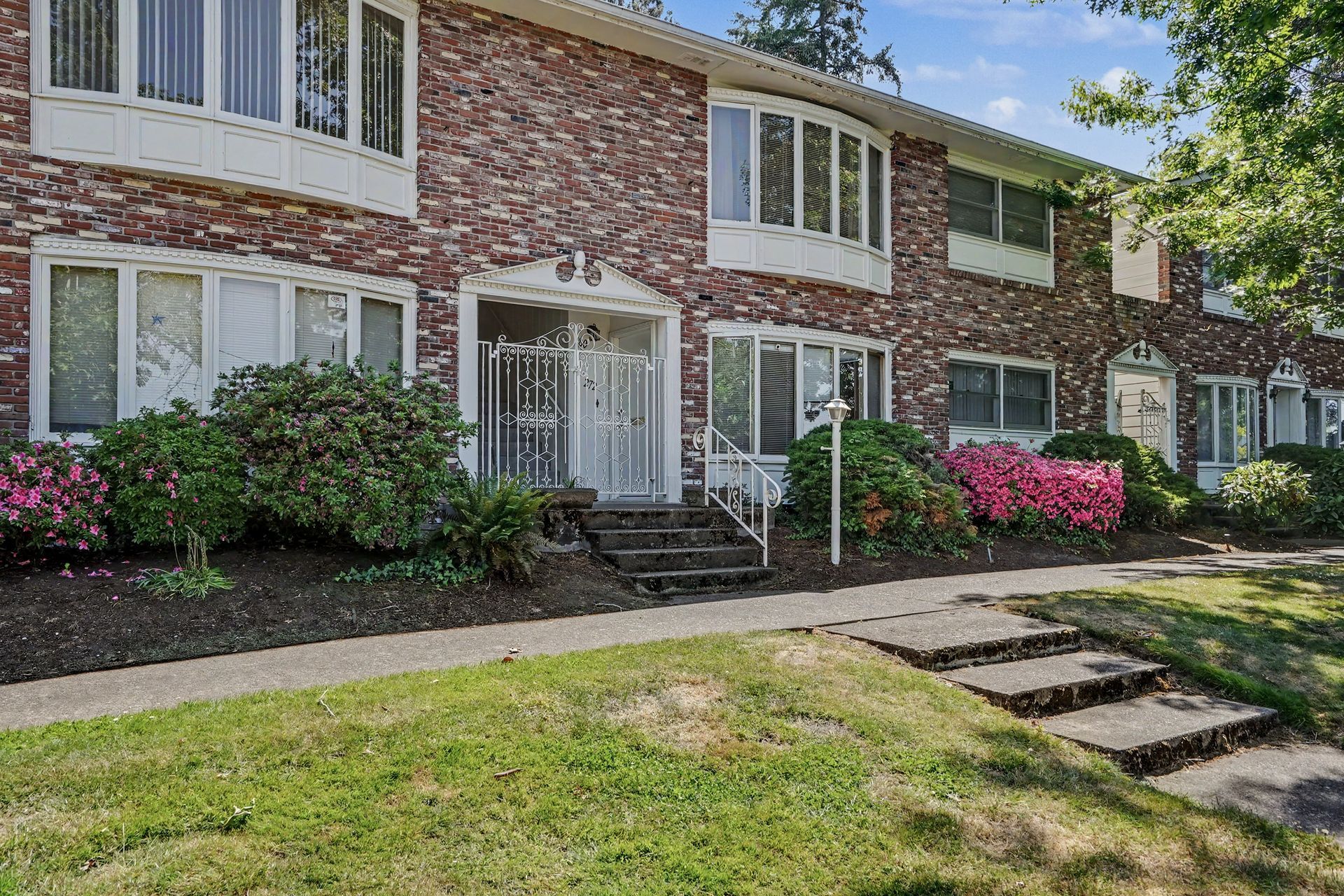 Courtyard apartment complex with swimming pool, white buildings, and patio seating in bright sunlight