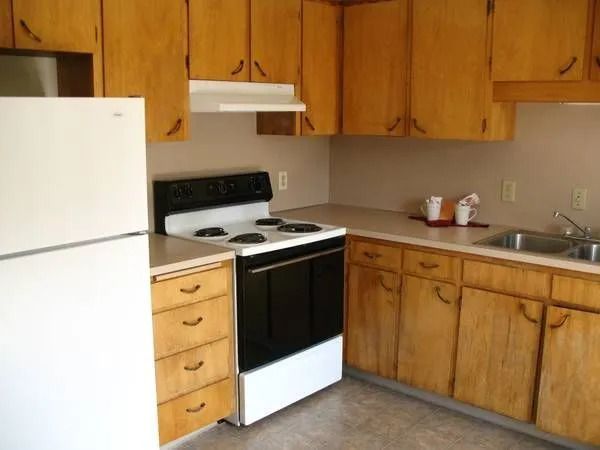 Small kitchen with wood cabinets, white refrigerator and stove, and a countertop with a sink.