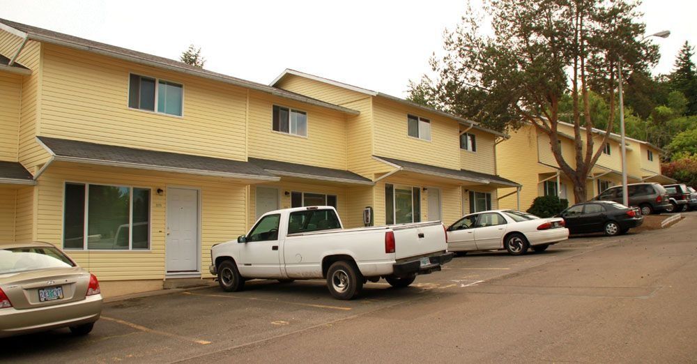 Apartment complex parking lot with several parked cars and a pickup truck