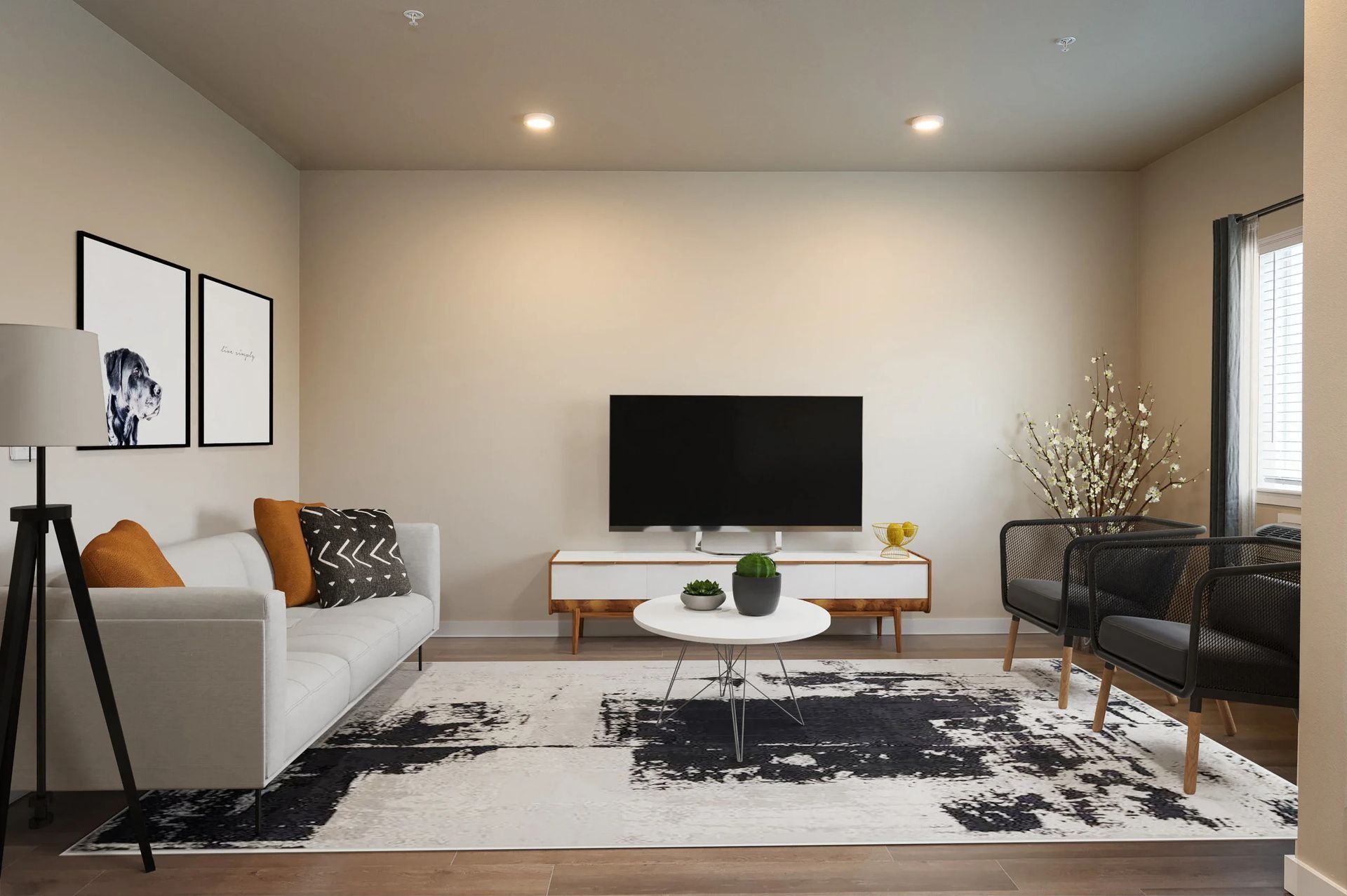 Modern living room with gray sofa, TV, coffee table, patterned rug, and a vase of white flowers.