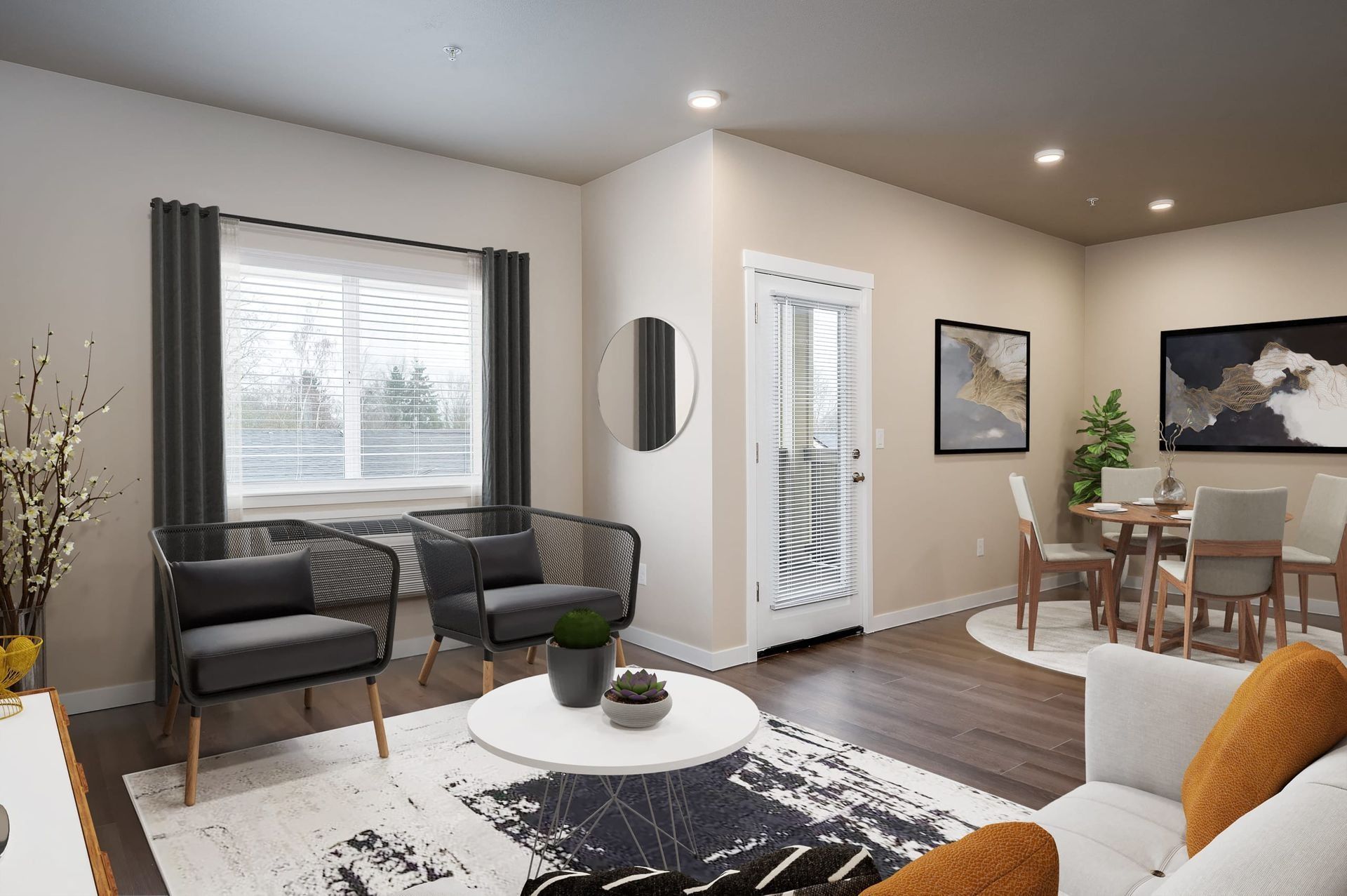 Bright living room with gray chairs, white coffee table, dining area, and large window with blinds