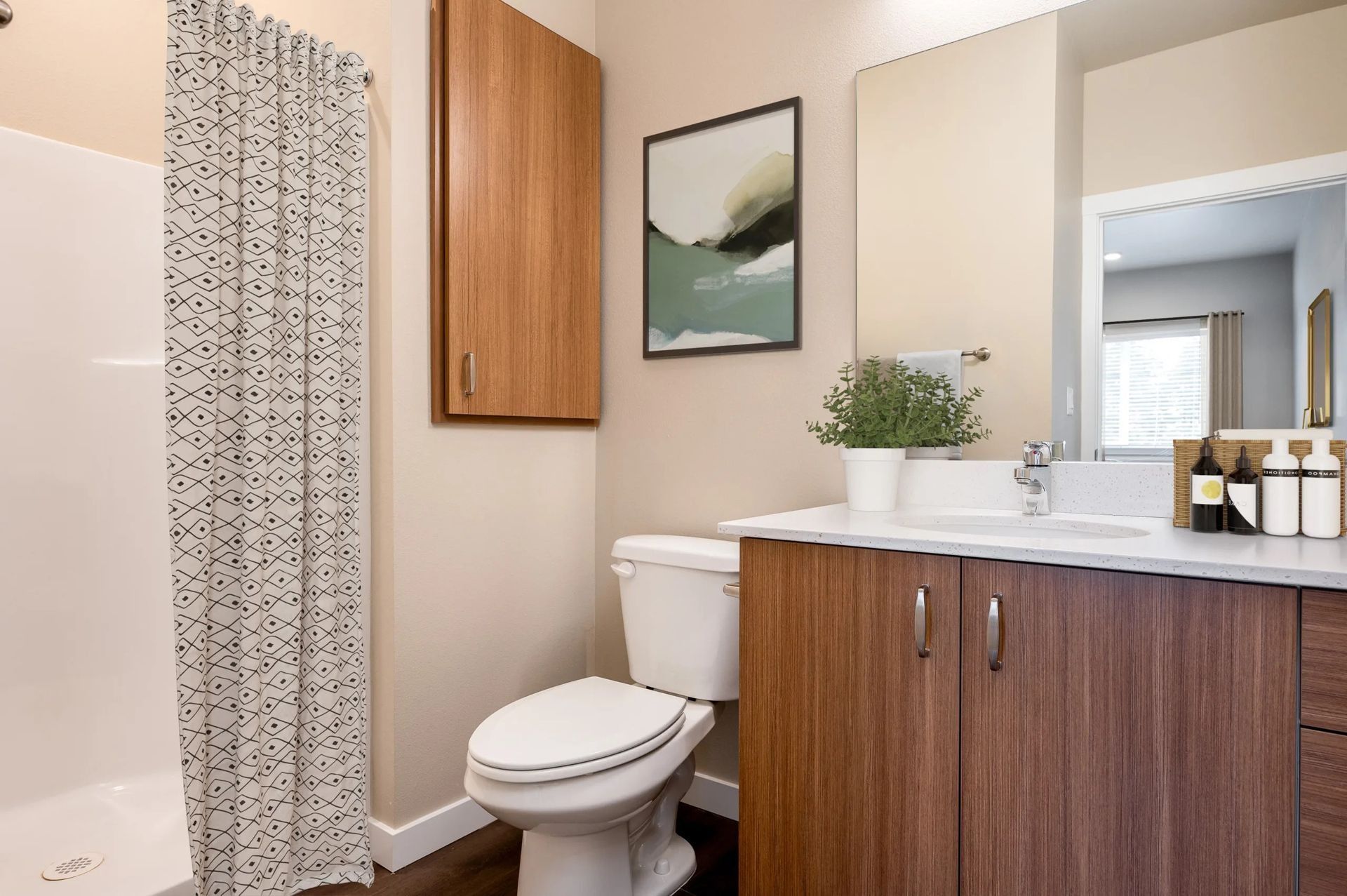 Modern bathroom with wood vanity, toilet, shower curtain, and framed wall art