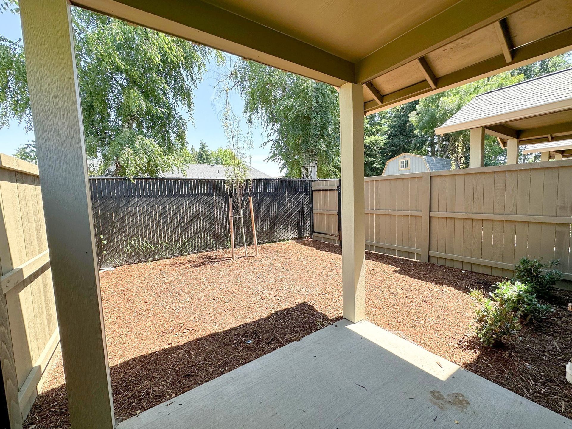 Covered patio overlooking a fenced backyard with gravel ground and small shrubs