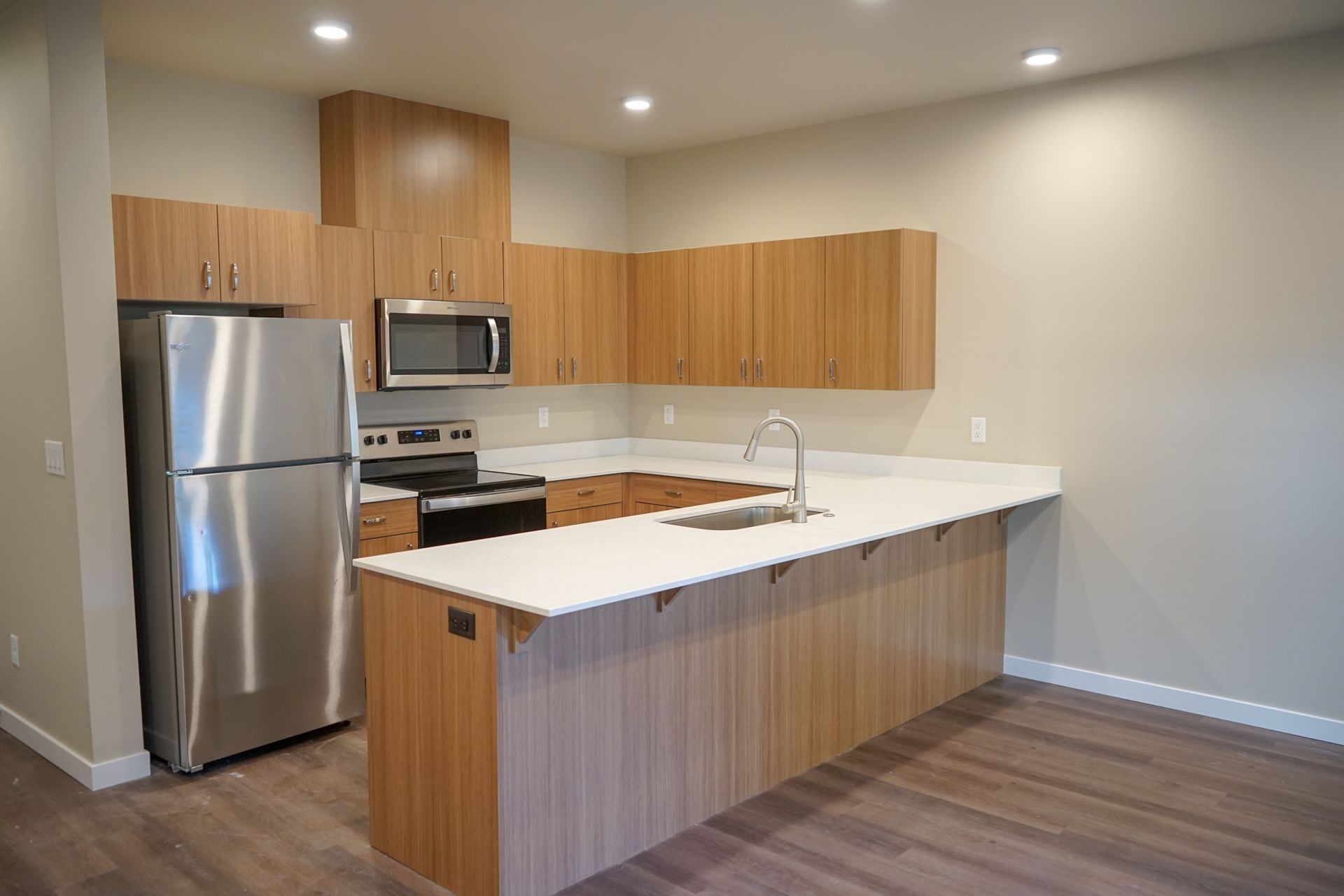 Modern kitchen with stainless steel appliances, wood cabinets, and a white island countertop