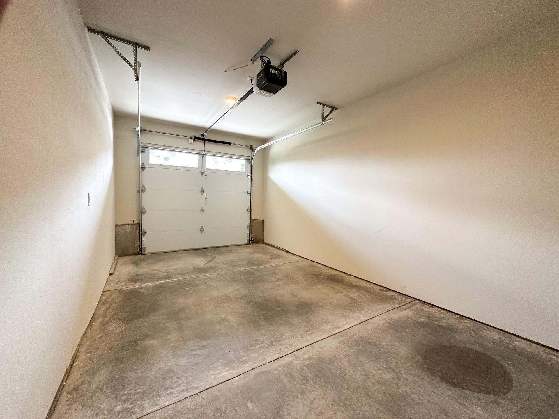 Empty residential garage with closed white door and concrete floor