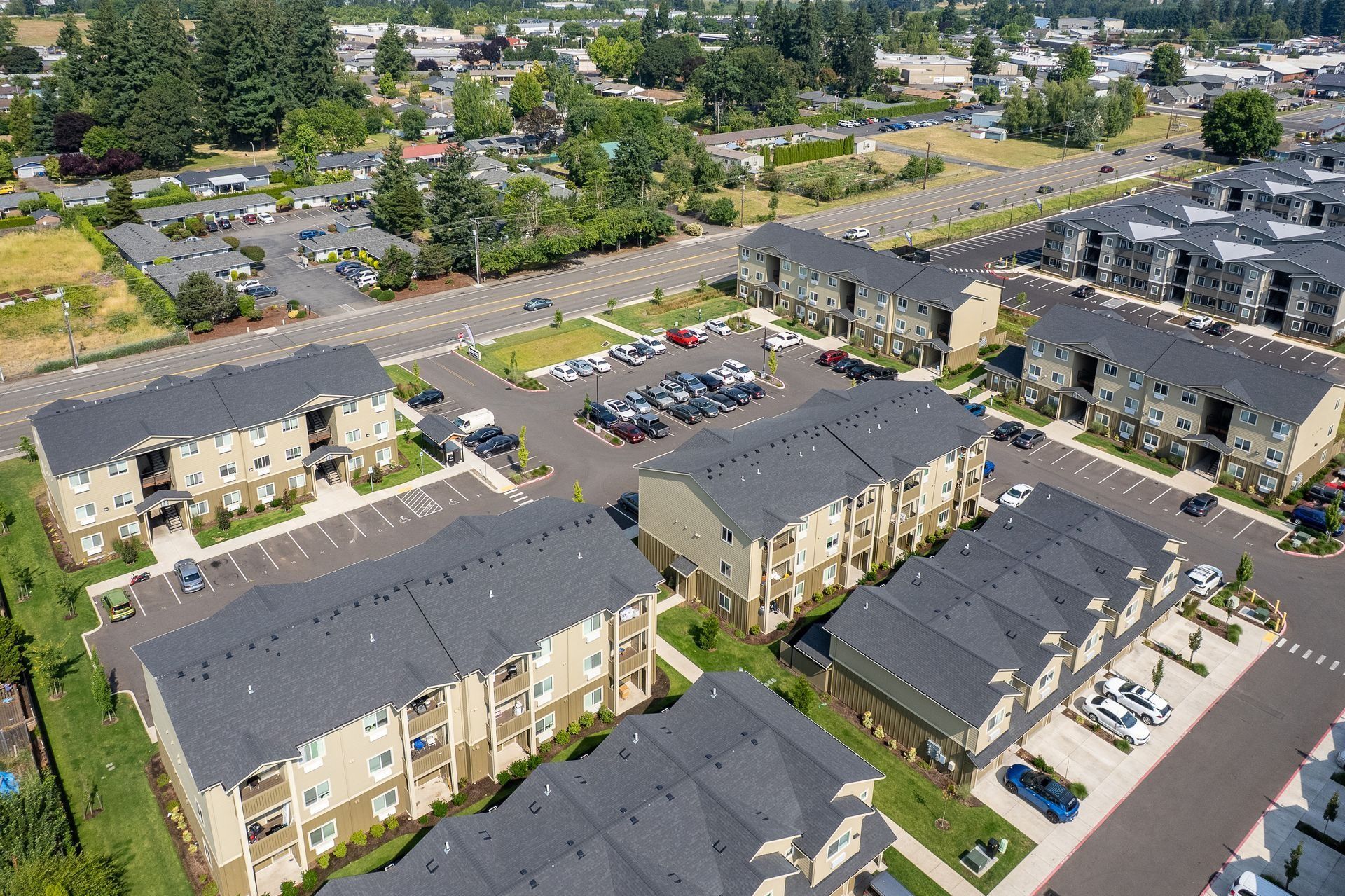 Aerial view of tan apartment buildings, parking lots, and trees in a suburban complex