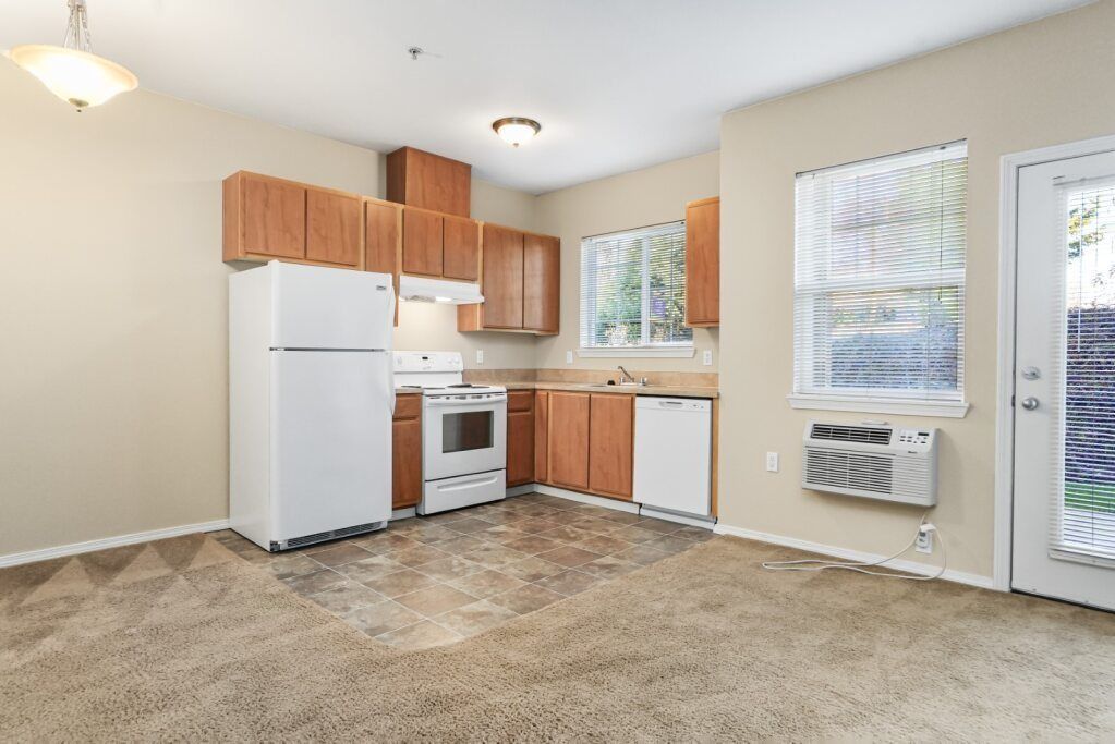 Small kitchen with white appliances, wood cabinets, and a sliding glass door to the outside.