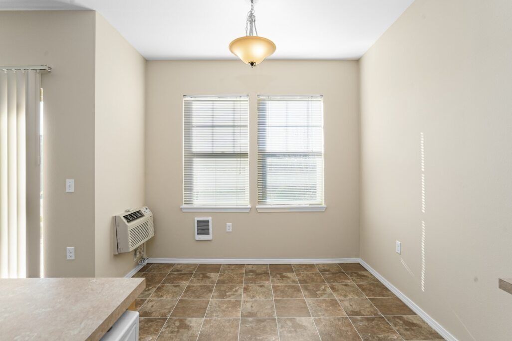 Empty beige dining room with tiled floor, window blinds, and ceiling light fixture